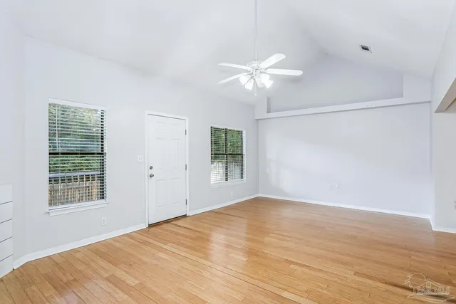 a view of an empty room with a window and wooden floor