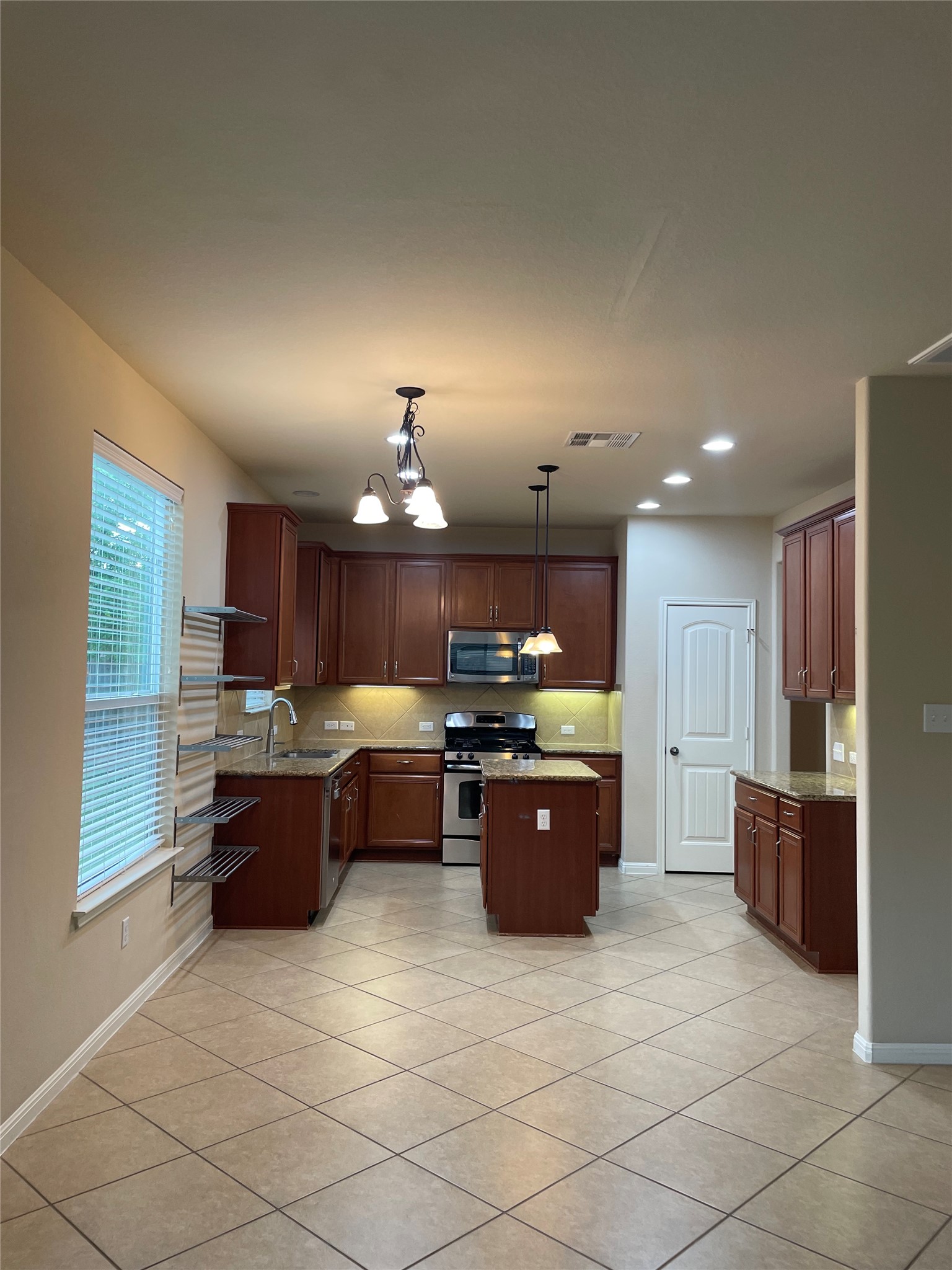 102 Sandy Lyle Cove Round Rock, TX 78664 - Photo 10 of 38 a large kitchen with a stove a refrigerator and a fireplace