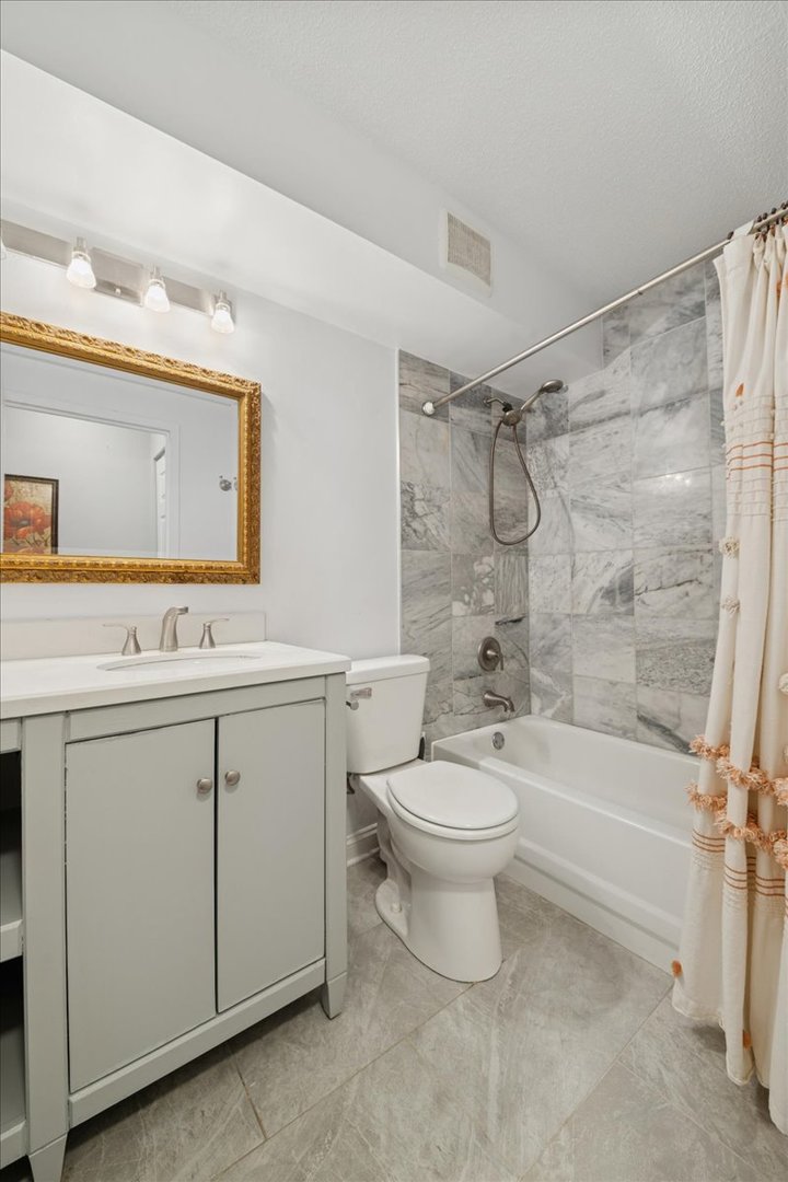 1800 Huntington Boulevard, Unit 212 Hoffman Estates, IL 60169 - Photo 11 of 15 a bathroom with a toilet a sink a mirror a bathtub and vanity