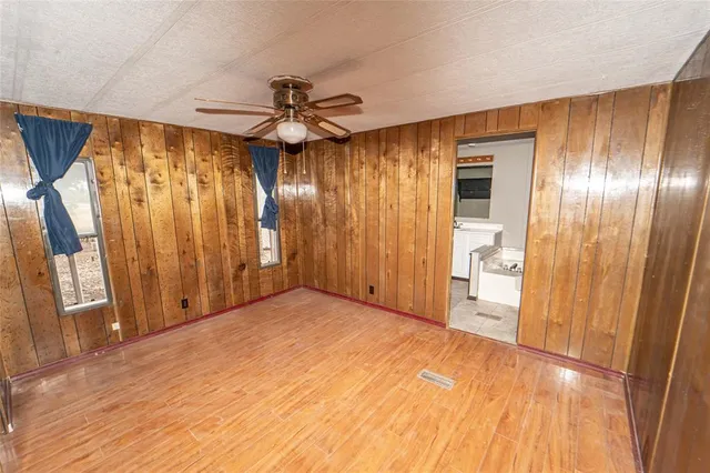 a view of empty room with wooden floor and fan