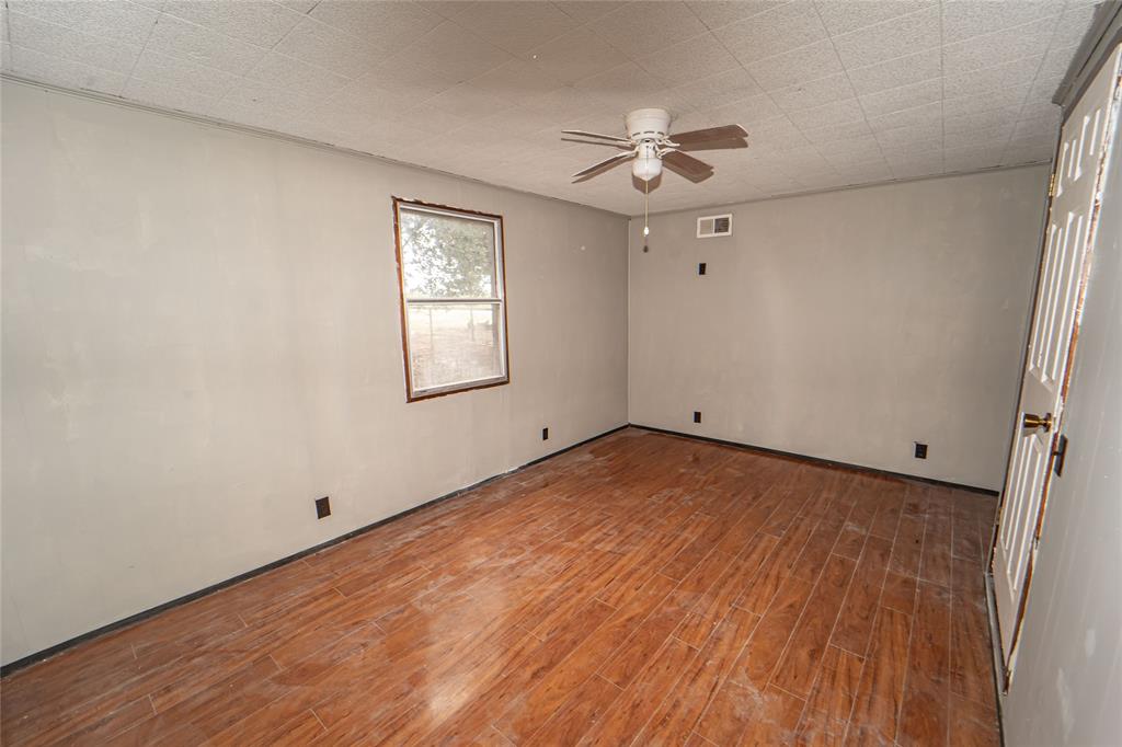 122 County Road 306 Breckenridge, TX 76424 - Photo 25 of 40 an empty room with wooden floor chandelier fan and windows