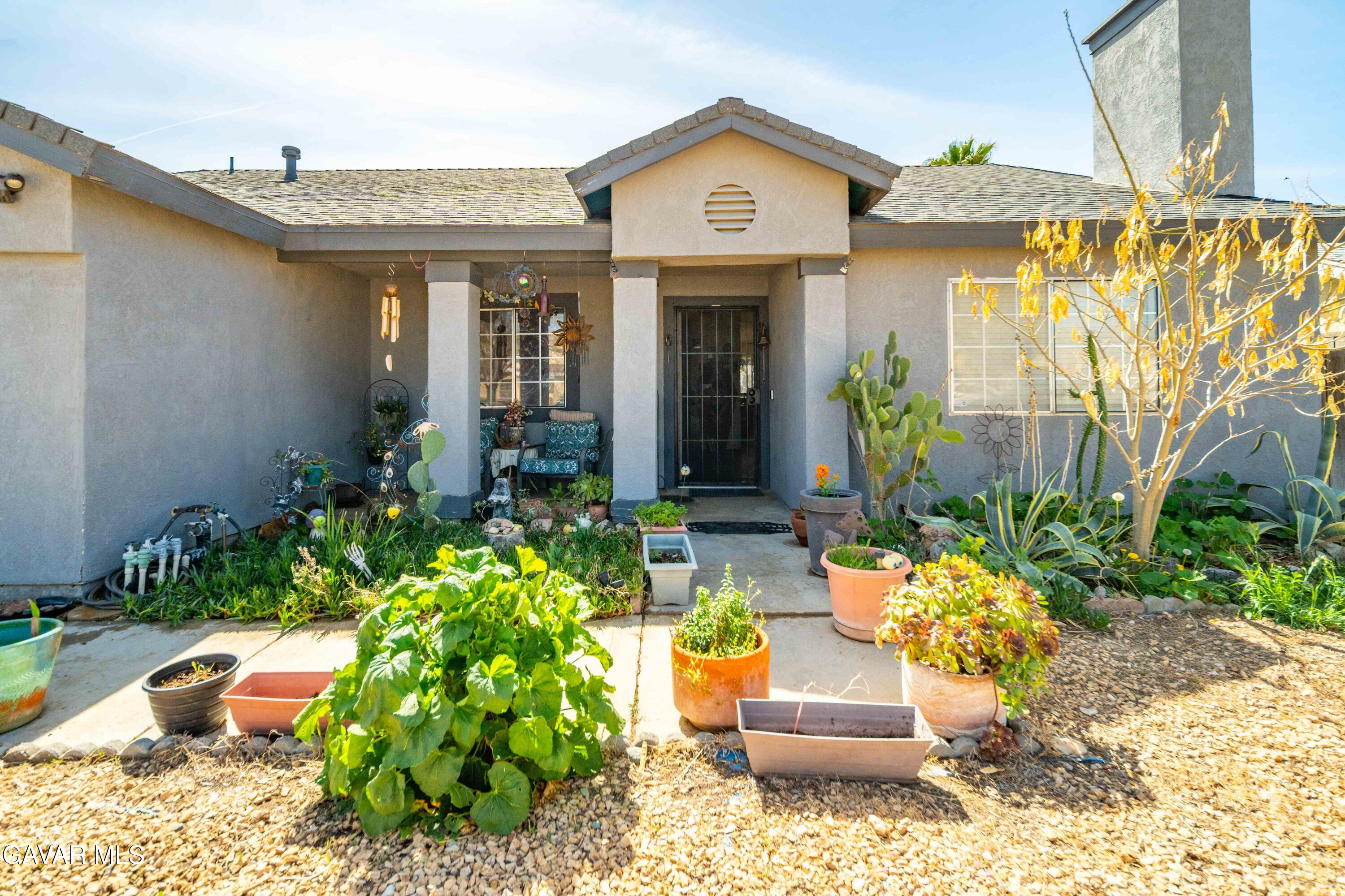 3112 Myrtle Street Rosamond, CA 93560 - Photo 1 of 49 a front view of a house with lots of potted plants