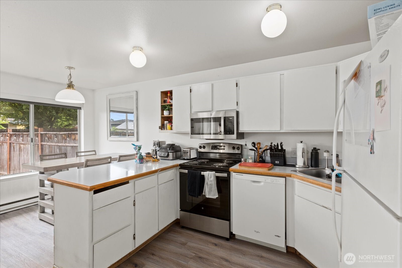 2826 Northeast 8th Street Renton, WA 98056 - Photo 7 of 20 a kitchen with stainless steel appliances granite countertop a sink dishwasher stove and white cabinets with wooden floor
