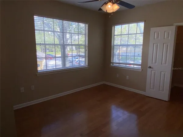 an empty room with wooden floor and windows