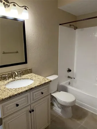 a bathroom with a granite countertop sink toilet a mirror and shower