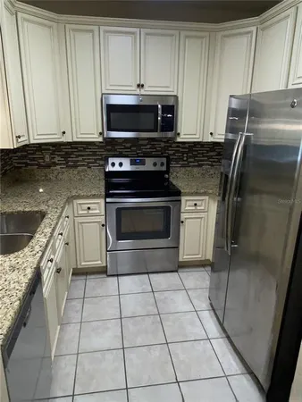 a kitchen with granite countertop a stove a microwave and a sink