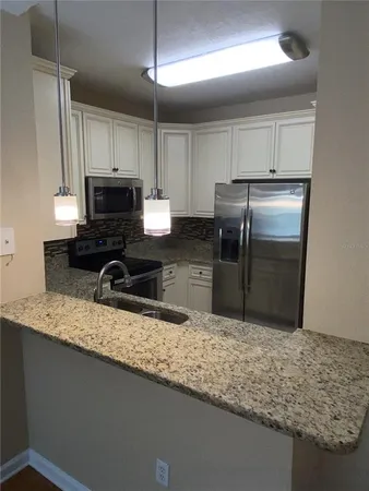 a kitchen with granite countertop a sink a counter top space appliances and cabinets