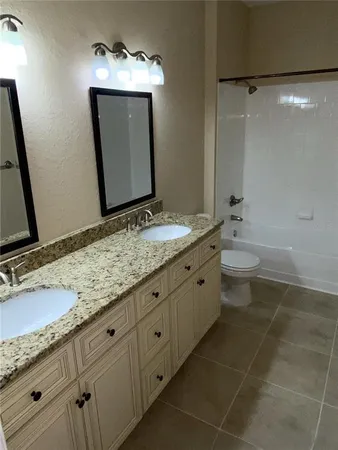 a bathroom with a granite countertop sink a toilet and a mirror