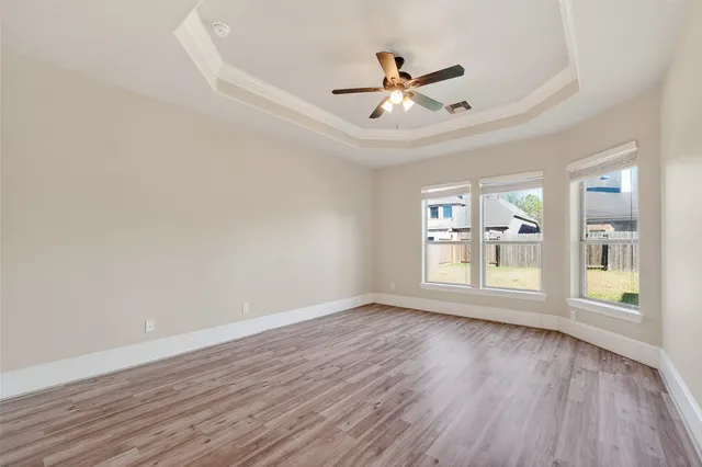 a view of an empty room with a window and wooden floor
