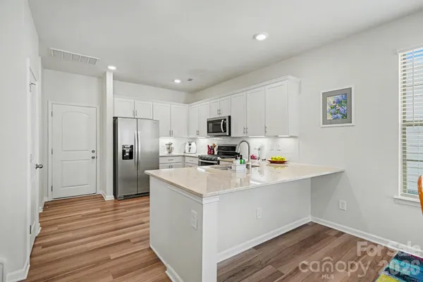 a kitchen with stainless steel appliances a refrigerator sink and white cabinets