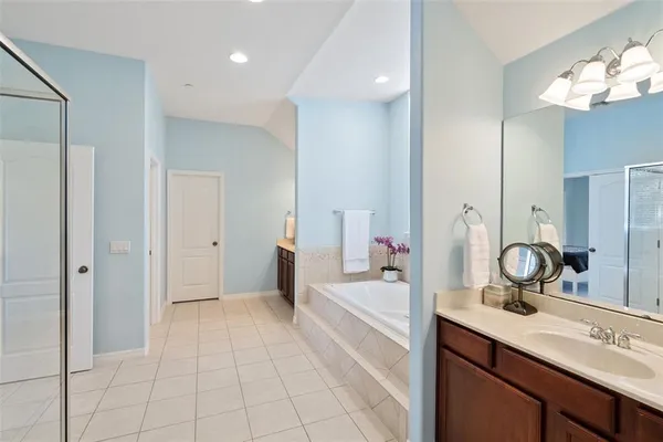 a spacious bathroom with a double vanity sink a mirror and a bathtub
