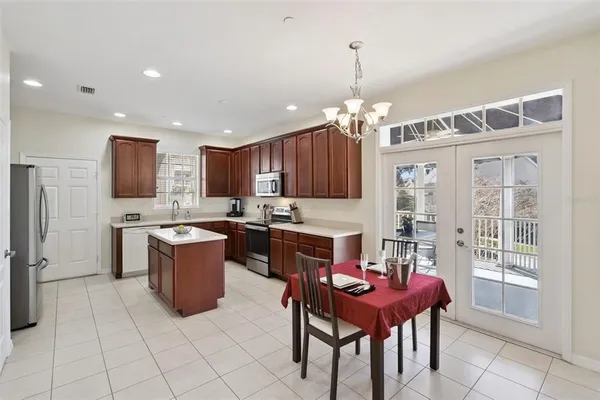 a kitchen with stainless steel appliances granite countertop a refrigerator a sink dishwasher a dining table and chairs with a large window