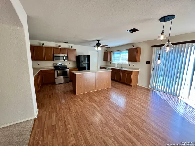 a living room with stainless steel appliances furniture a flat screen tv and refrigerator