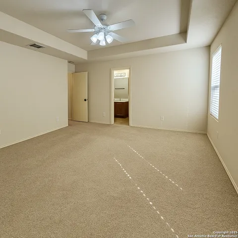an empty room with chandelier fan and windows
