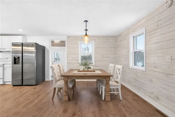 an empty room with wooden floor windows and kitchen view