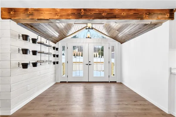 a view of empty room with wooden floor and kitchen view