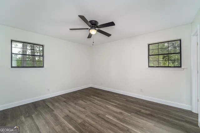 a view of empty room with wooden floor and fan