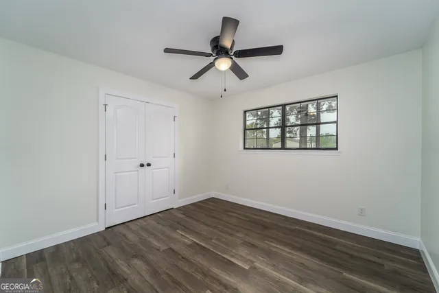 a view of empty room with wooden floor and ceiling fan