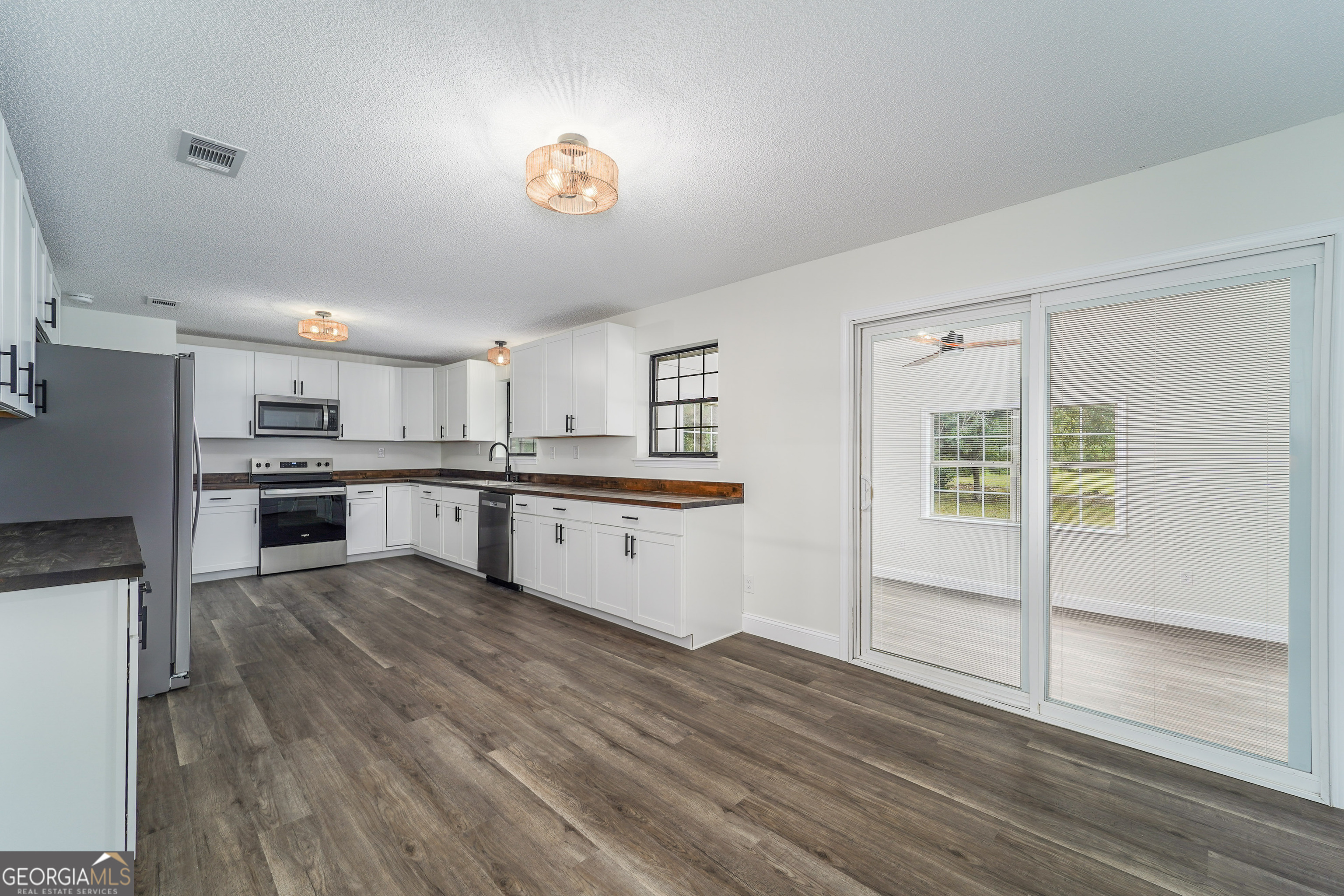 5406 Blue Spruce Road Blackshear, GA 31516 - Photo 10 of 28 a large kitchen with kitchen island a stove a sink dishwasher and white cabinets with wooden floor