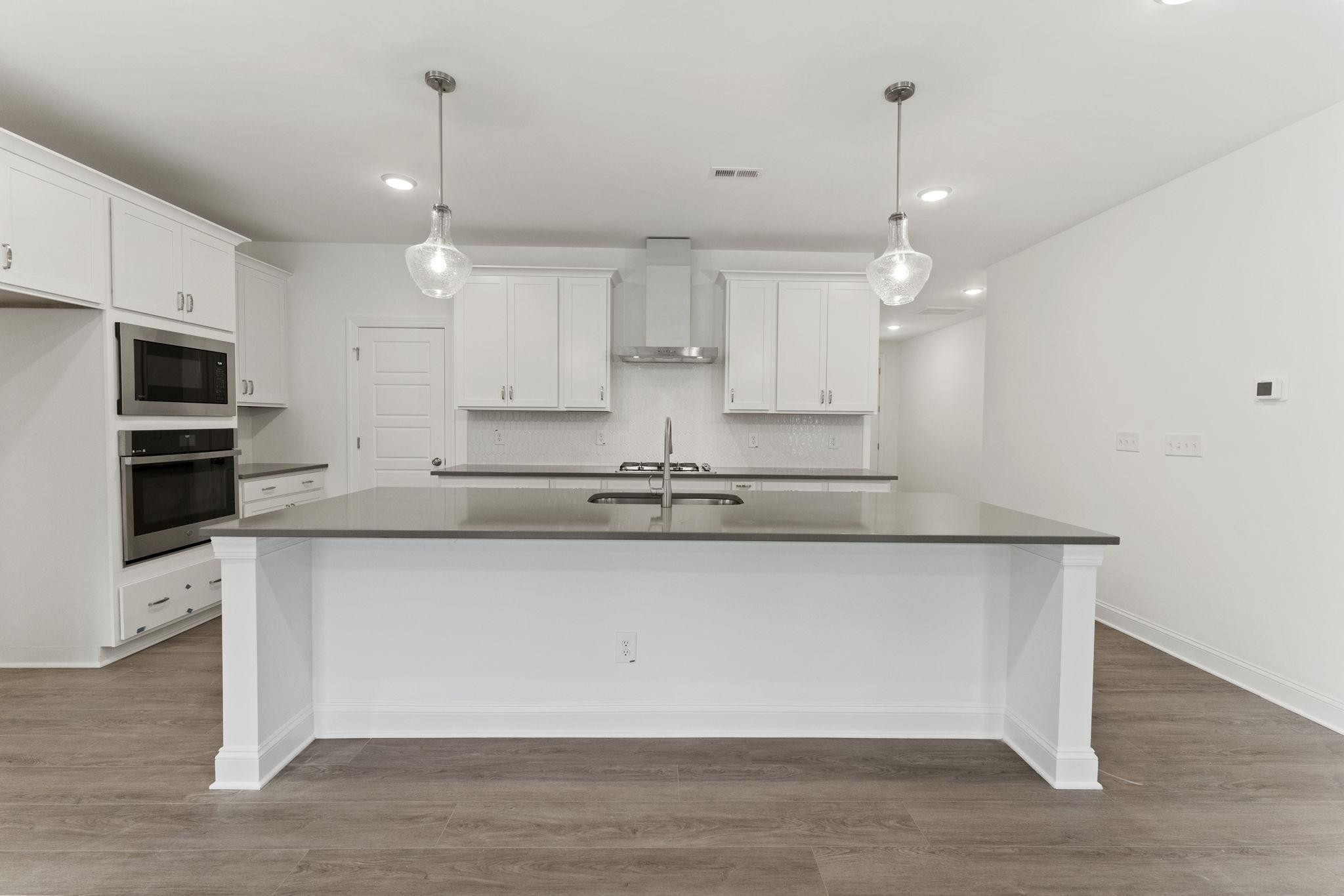 2128 Voekler Street Apex, NC 27502 - Photo 19 of 27 a large kitchen with stainless steel appliances granite countertop a stove a sink and a microwave
