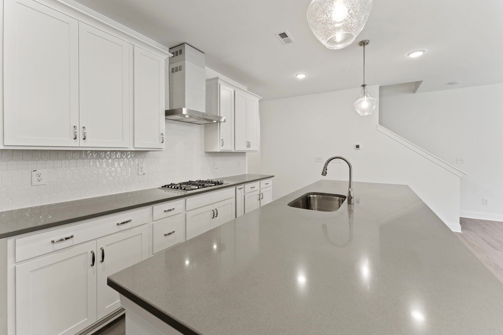 2128 Voekler Street Apex, NC 27502 - Photo 6 of 27 a kitchen with stainless steel appliances granite countertop a sink a stove and white cabinets with wooden floor