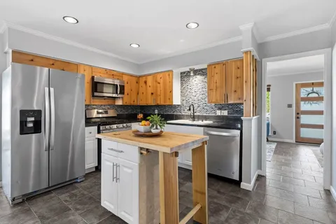 a kitchen with a refrigerator a stove top oven and a window