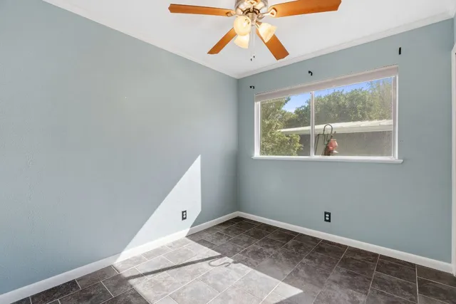 an empty room with a window and a fan