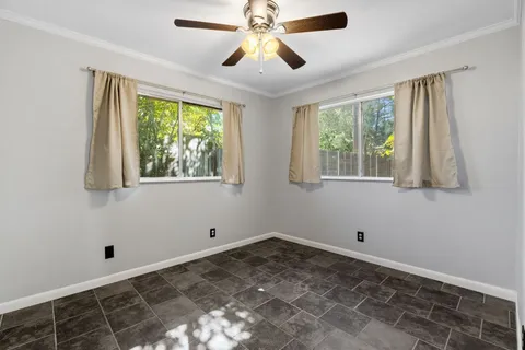 a view of empty room with window and ceiling fan