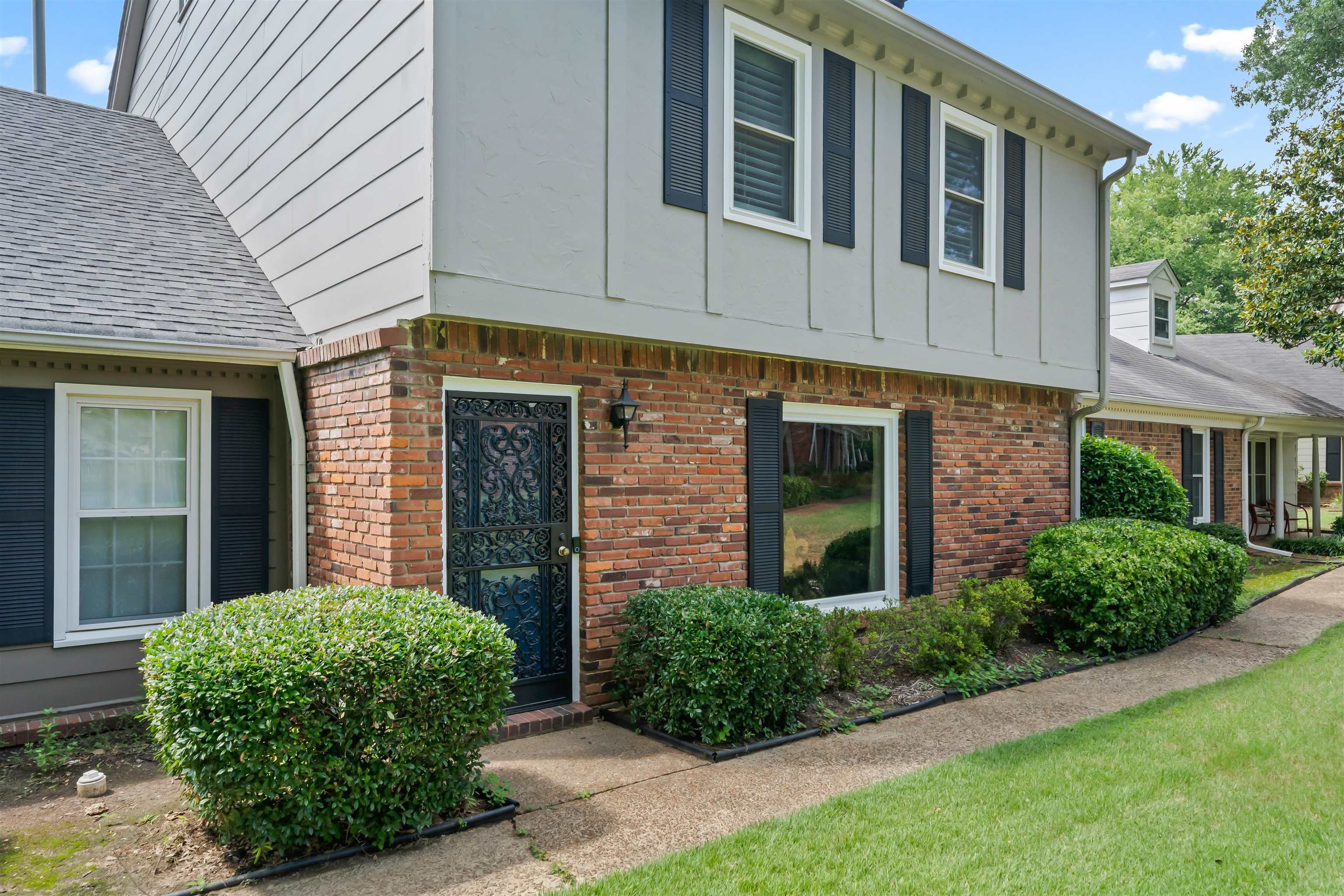 6943 Fords Station Road, Unit 64 Germantown, TN 38138 - Photo 30 of 30 Brick and siding exterior featuring dark shutters, an ornate security door, and mature shrubbery