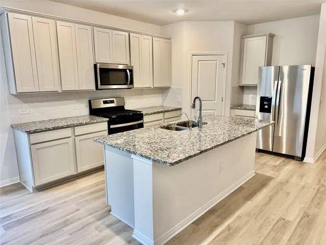 a kitchen with granite countertop stainless steel appliances a stove microwave and refrigerator