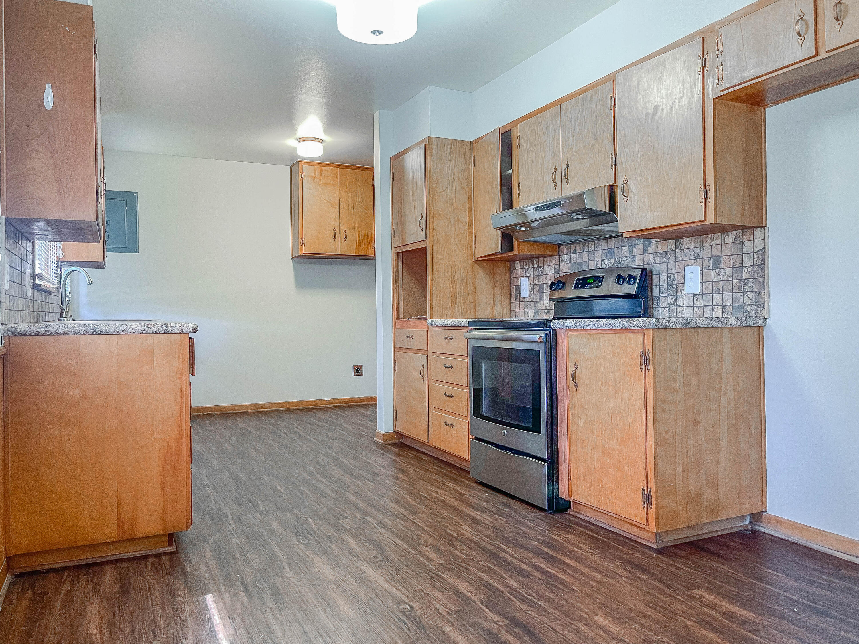 3419 53rd Street Lubbock, TX 79413 - Photo 4 of 11 a kitchen with stainless steel appliances granite countertop a stove top oven a refrigerator a sink and dishwasher with wooden floor