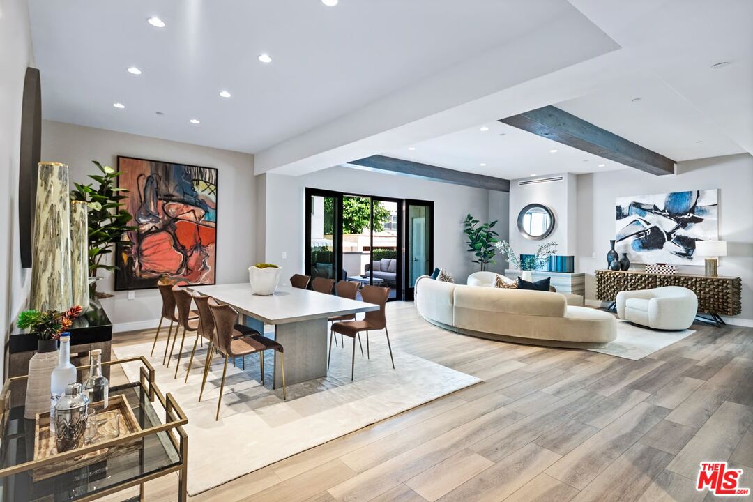 a living room with furniture kitchen view and a large window