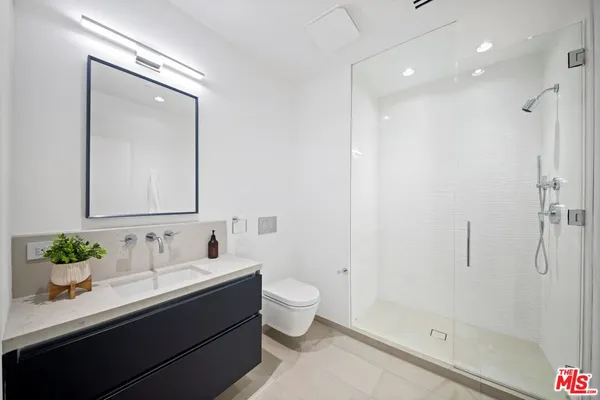 a bathroom with a sink a toilet a shower and a mirror