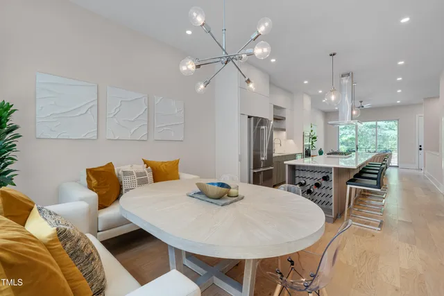 a kitchen with stainless steel appliances kitchen island granite countertop a dining table chairs and a refrigerator