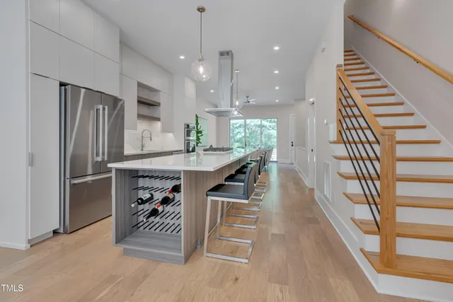 a kitchen with stainless steel appliances kitchen island granite countertop a refrigerator a stove and a wooden floors