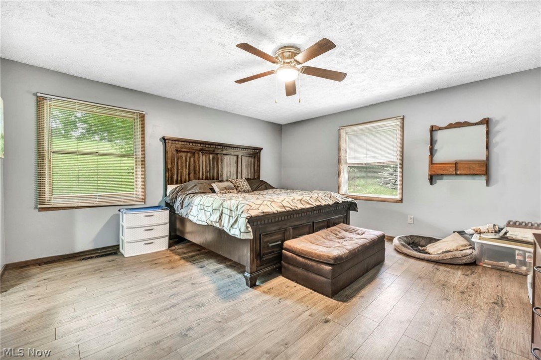 4560 Arrow Road Northwest Carrollton, OH 44615 - Photo 15 of 41 Bedroom with hardwood / wood-style flooring, multiple windows, a textured ceiling, and ceiling fan