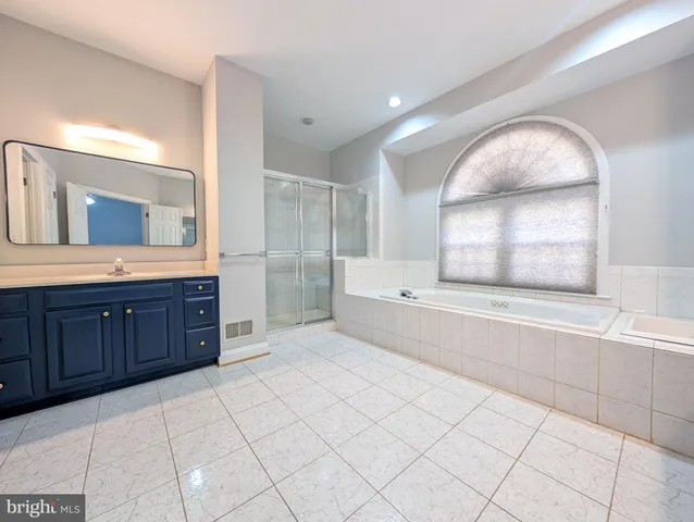 a spacious bathroom with a granite countertop sink mirror and bathtub