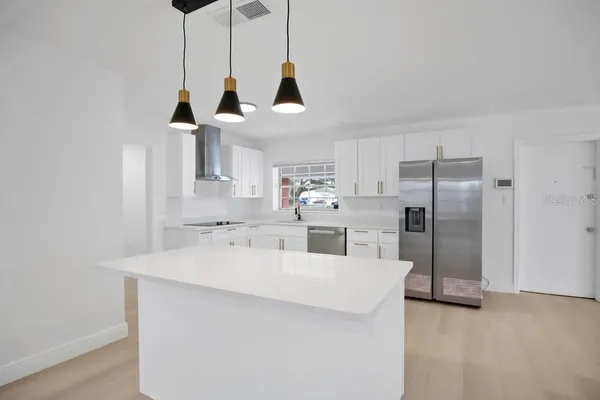 a view of a kitchen with stainless steel appliances granite countertop a sink a stove and a refrigerator