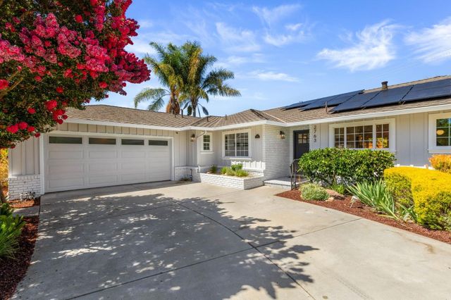 a front view of a house with a yard and potted plants