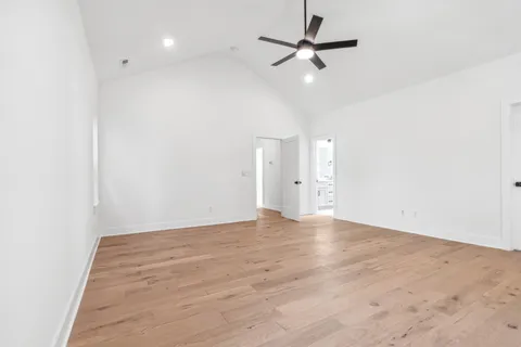 an empty room with wooden floor ceiling fan and window