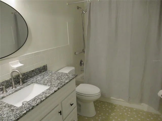 a bathroom with a granite countertop toilet sink and mirror