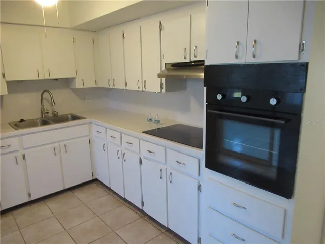 a kitchen with white cabinets and sink