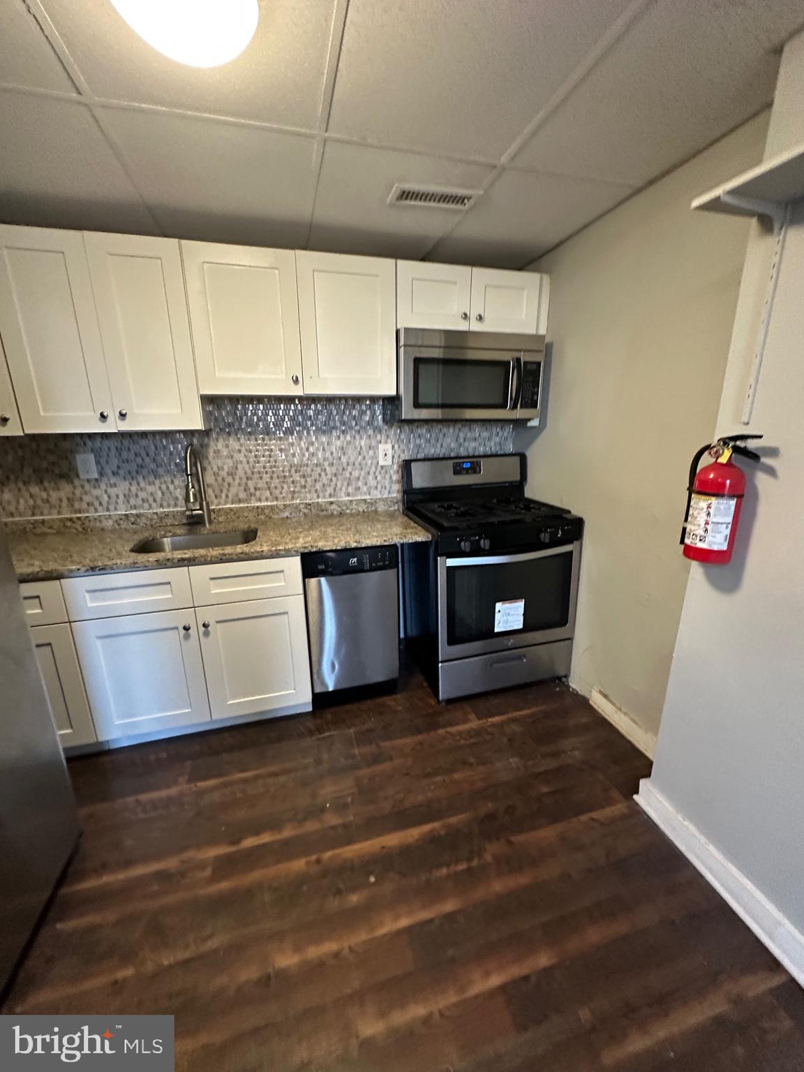 525-527 Penn Street, Unit 1B Camden, NJ 08102 - Photo 2 of 10 a kitchen with stainless steel appliances granite countertop a stove a sink and a microwave