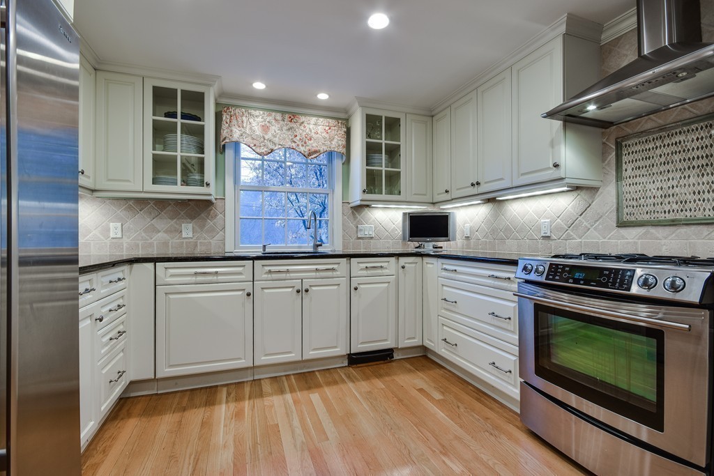 33 Oakridge Road Wellesley, MA 02481 - Photo 11 of 27 a kitchen with stainless steel appliances granite countertop a stove a sink and white cabinets with wooden floor