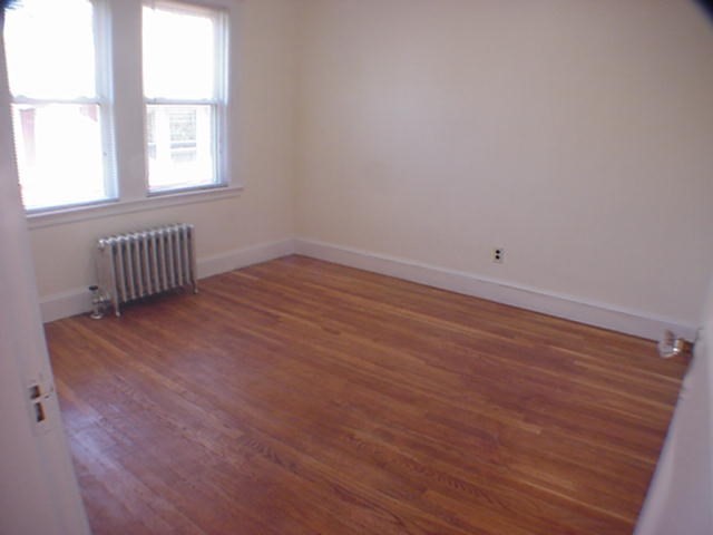 8-10 Kenrick Street, Unit 10 Boston, MA 02135 - Photo 23 of 28 an empty room with wooden floor and windows