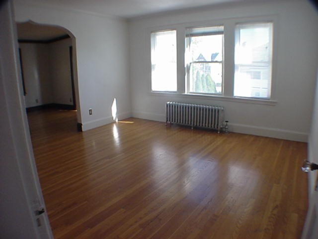 8-10 Kenrick Street, Unit 10 Boston, MA 02135 - Photo 9 of 28 an empty room with wooden floor and windows