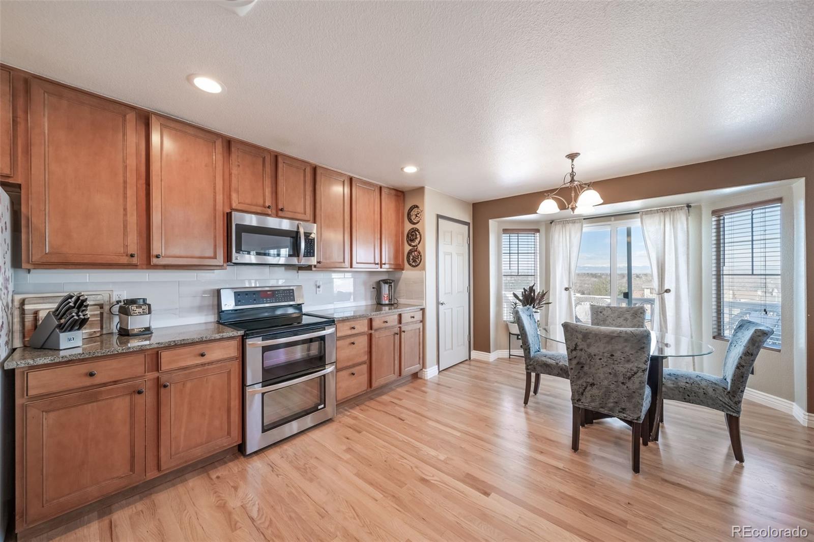 3041 South Jericho Way Aurora, CO 80013 - Photo 16 of 46 a kitchen with microwave a stove top oven a sink dishwasher a dining table and chairs with wooden floor