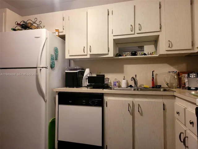 a kitchen with stainless steel appliances granite countertop a refrigerator a sink and white cabinets