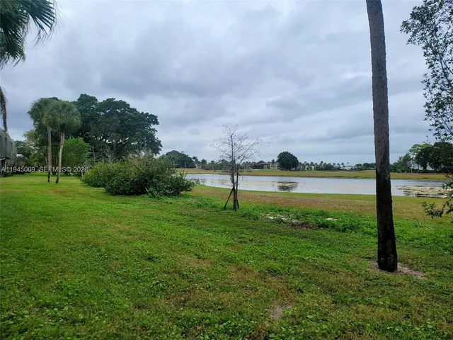 a view of a lake with a big yard and palm trees