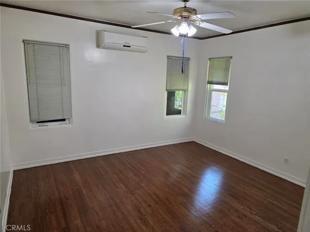an empty room with wooden floor chandelier fan and windows